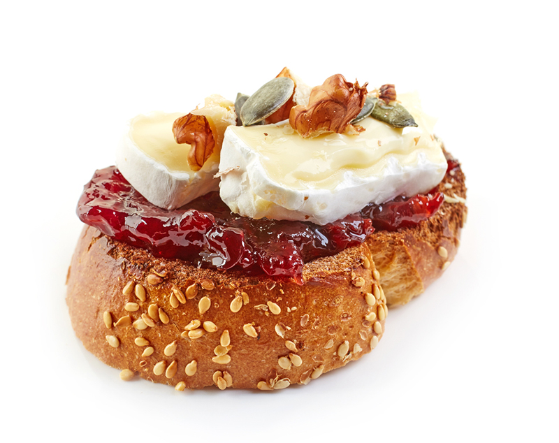 Toasted bread slice with cherry jam and brie cheese with nuts