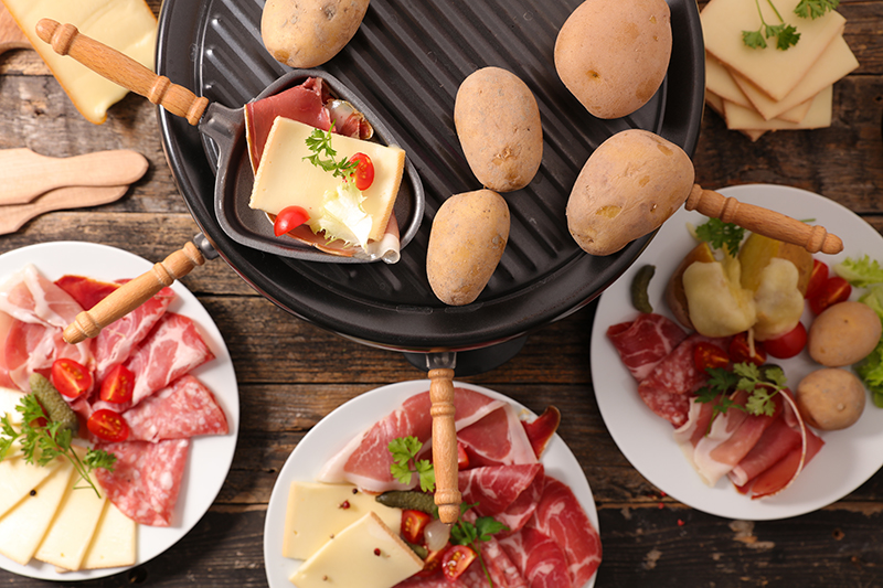 Raclette cheese with boiled potatoes and salami